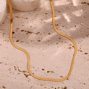 Macro shot of 2mm 18K gold plated snake chain necklace on minimalist stone background