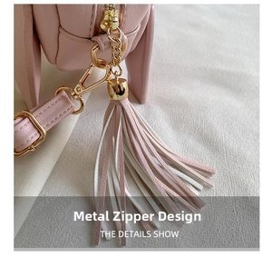 Detailed view of pink bag with gold hardware zipper and two-tone tassel charm