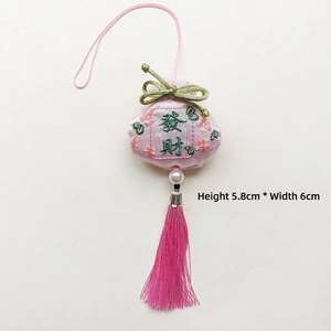 Detalle de bolsa de la suerte bordada rosa con borla verde y caracteres tradicionales