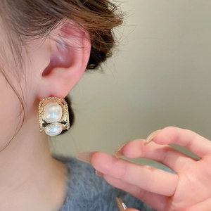 Gros plan de boucles d'oreilles élégantes en or et perles en C sur l'oreille du modèle
