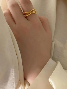 Macro detail of gold beaded crisscross ring shown on hand with elegant styling