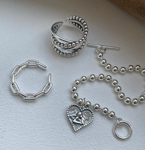 Close-up of 925 sterling silver jewelry set with layered rings and heart pendant bracelet