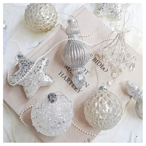 Macro shot of silver and white snowflake ornaments on book with festive pearls