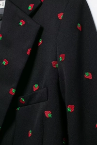 Gros plan détaillé d'une broderie de fraises de qualité sur le tissu d'un blazer noir