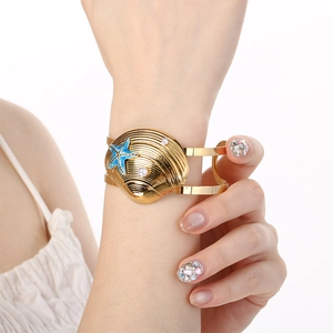 Detail of gold ocean style shell and starfish bangle featuring blue accents and pearls