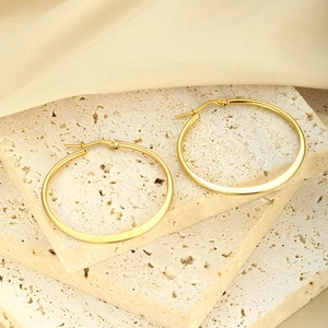 Macro shot of gold-plated hoop earrings on stone base with satin fabric detail