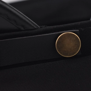 Macro detail of black leather strap with matte bronze button on high-density fabric