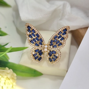 Detailed close-up of golden butterfly ring with blue rectangle stones and clear crystals