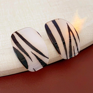 Detail shot of square leopard print earrings with translucent amber finish and silver studs