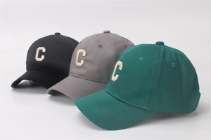Detailed close-up showing embroidered white letters on cotton baseball caps in multiple colors