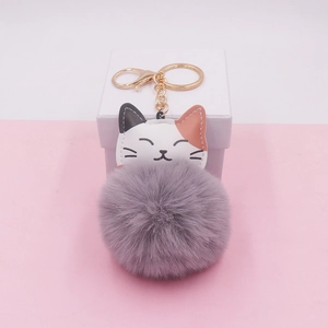 Close-up of a tricolor cat PU leather keychain with a large grey fluffy fur pompom