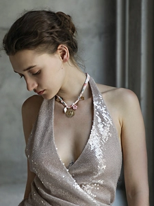 Close-up of 18K gold sun face pendant on pink floral ribbon necklace worn by model
