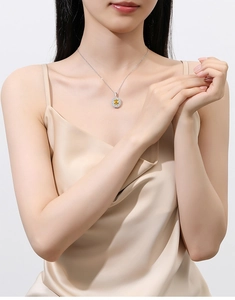 Close-up of a silver necklace with a yellow oval gemstone pendant worn by a model