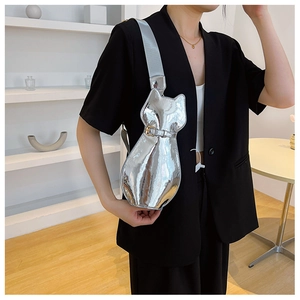 Detail of a bright silver cat-shaped crossbody bag with adjustable grey strap and gold buckle