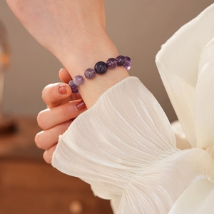 Detailansicht eines lila Amethyst-Perlenarmbands am Handgelenk mit eleganter Seidenmanschette