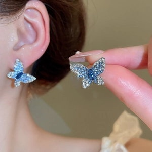 Détail macro de boucles d'oreilles papillon avec cristaux bleus et tiges en argent