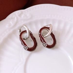 Détail de boucles d'oreilles argentées avec pendentif ovale bordeaux et relief floral