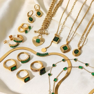 French vintage gold jewelry set with emerald green stones on white silk background