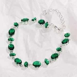 Close-up of green oval-cut gemstones with silver prong settings and adjustable chain