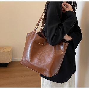 Detail view of large brown faux leather tote bag with elegant gold metal accent