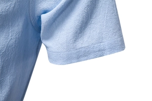 Detailed close-up of light blue cotton linen shirt cuff showing woven texture and stitching