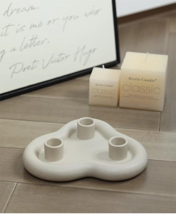 Détail d'un bougeoir en céramique blanc crème à trois têtes au design moderne ondulé