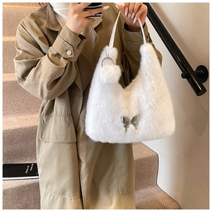 Detail of white faux fur handbag with silver butterfly charm and rhinestone ring pendant