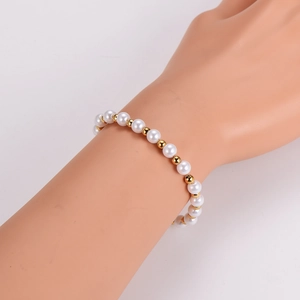 Minimalist pearl bracelet with white pearls and gold beads on a wrist model