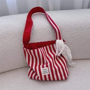 Detail of red striped canvas tote bag with white lace bow and elegant fabric label
