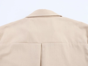 Detail of beige cotton linen blouse showing back yoke stitching and fabric texture