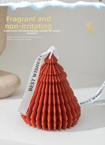 Macro shot of red geometric origami Christmas tree candle with printed ribbon decoration