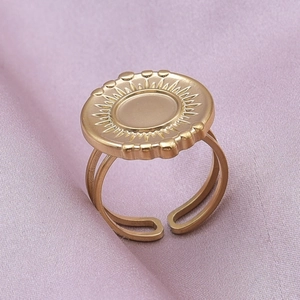 Macro shot of gold sunburst pattern ring with adjustable open band on purple silk background