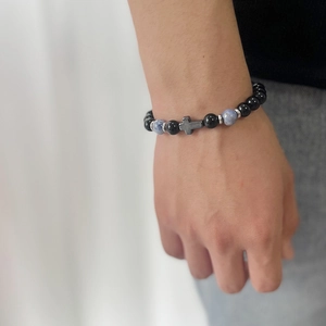 Close-up of beaded bracelet with blue tiger eye stones and silver cross on wrist