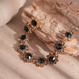 Detail of vintage gold bracelet with deep blue floral crystal on a beige stone surface