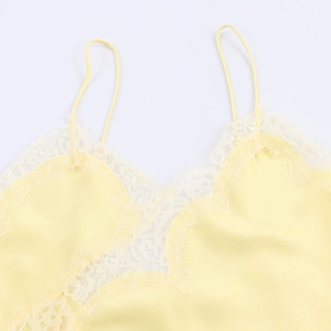 Detailed macro view of pale yellow satin top with delicate lace trim on the neckline