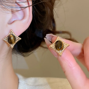 Macro shot of vintage star studs with oval tiger eye stones and gold textured metal