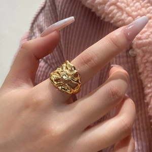 Détail d'une bague dorée au fini métal liquide avec une texture de lave fondue
