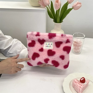 Detailed view of pink plush makeup bag with heart patterns and soft fabric texture