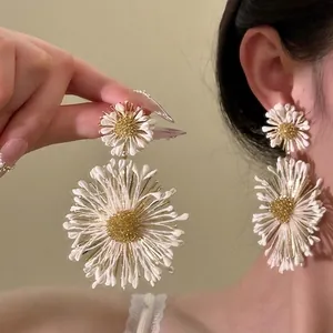 Macro detail of large daisy tassel earrings with 3D white petals and golden stamen studs