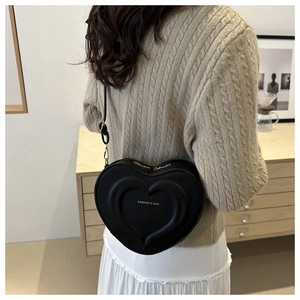 Detail of black heart-shaped crossbody bag with embossed pattern and fashion text