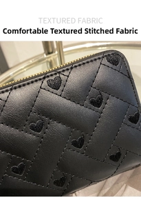Close-up of black quilted leather texture featuring elegant heart embroidery and zip detail