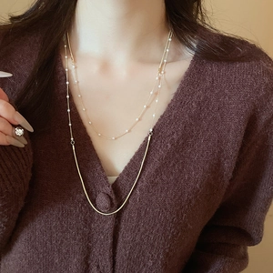 Detail of layered gold snake chain necklace with white pearls on a model