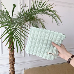 Detail of light green bubble canvas cosmetic bag with textured puff fabric and logo label