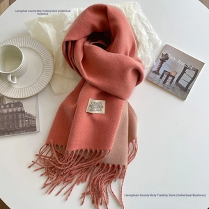 Detail of coral pink cashmere-like scarf showing soft texture, fringe, and UNDERSON label