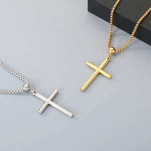 Detail of polished gold and silver cross necklaces with classic box chains on gray background