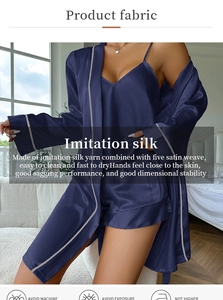 Three-piece dark blue silk satin pajama set with robe camisole and shorts in bedroom setting