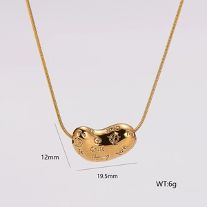 Detail of gold bean pendant with engraved letters on a polished snake bone chain