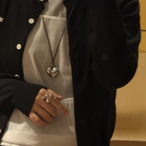 Detail of silver heart pendant necklace and hollow stackable ring on model skin