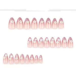 Detail of almond-shaped pink gradient press-on nails with white flowers and silver glitter