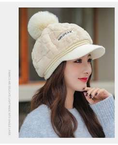 Detailed texture of women's plush cream-colored knit cap with soft fur pom-pom detail